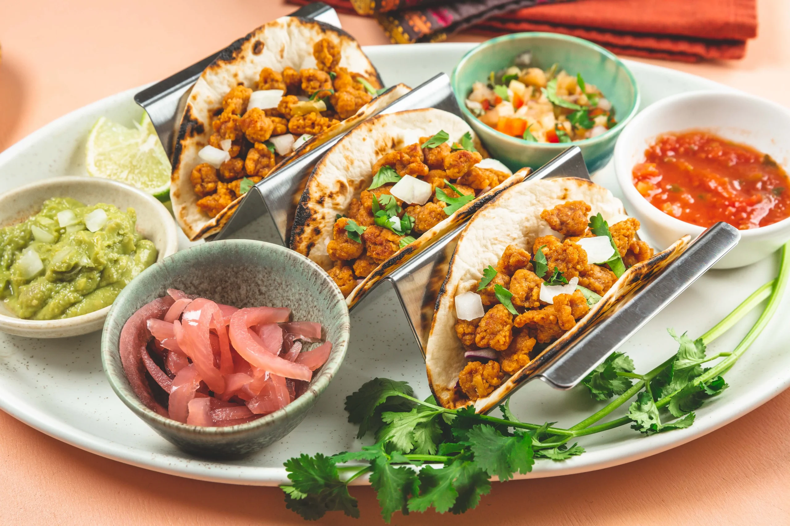 A serving of tacos arranged on a plate, accompanied by salsa and assorted condiments for added flavor.