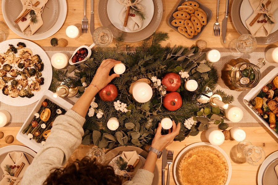 Hands placing lighted candles on a holiday dinner table set up