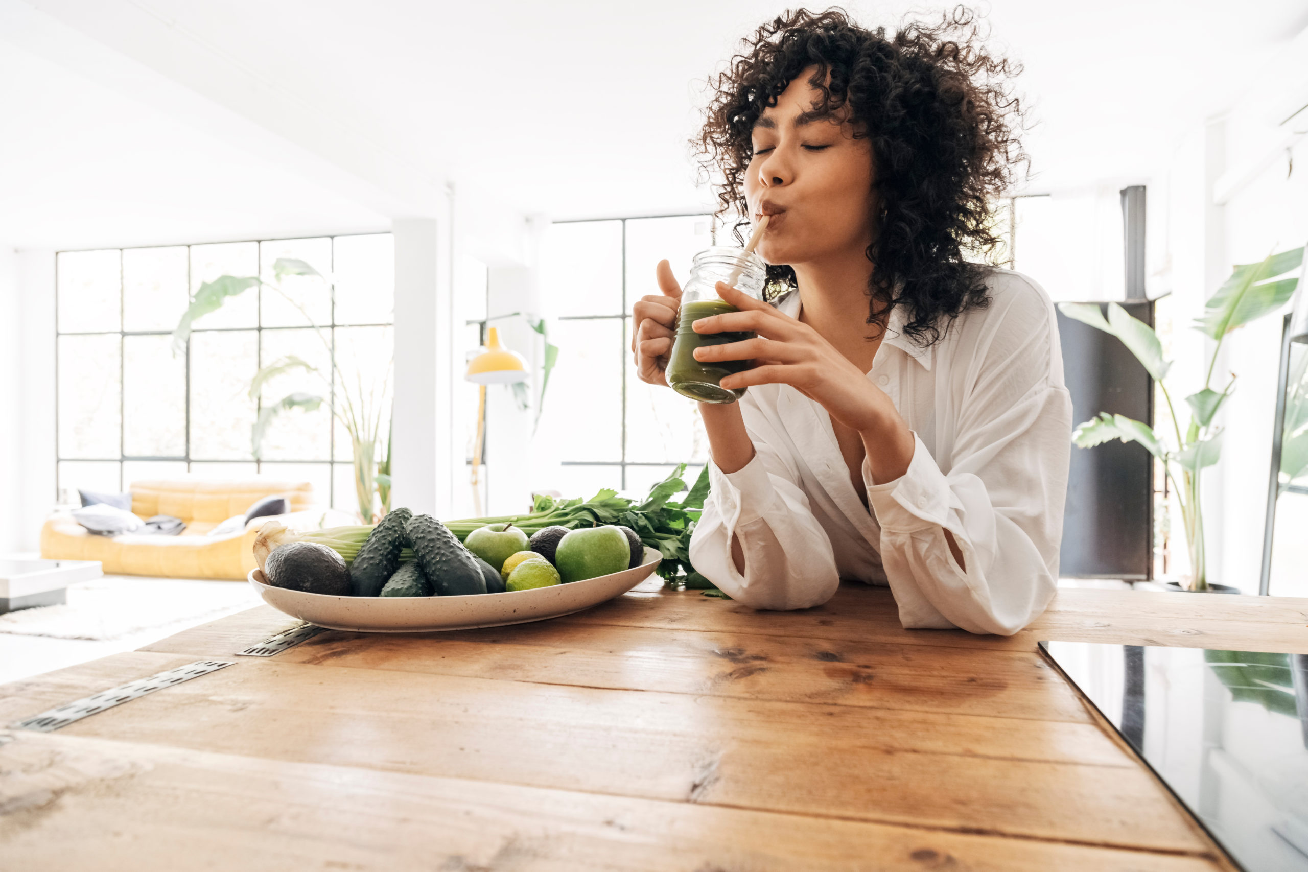 Young african american woman drinking green juice