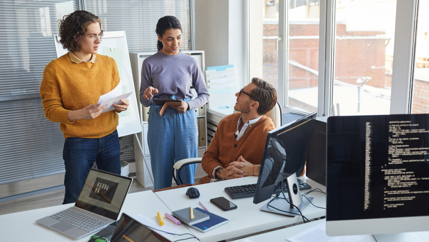 Two men and one woman in an office room having a discussion