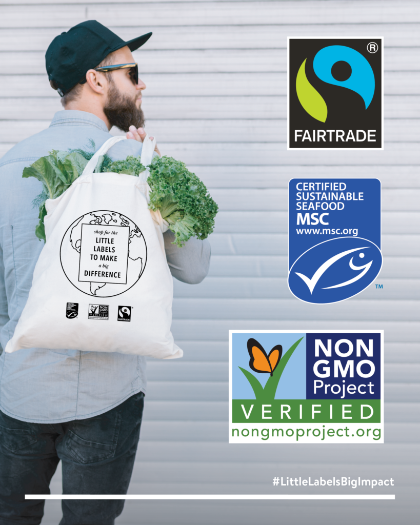 White man carrying a grocery canvas tote bag with Little Labels, which includes Fairtrade America, MSC, and Non-GMO Project