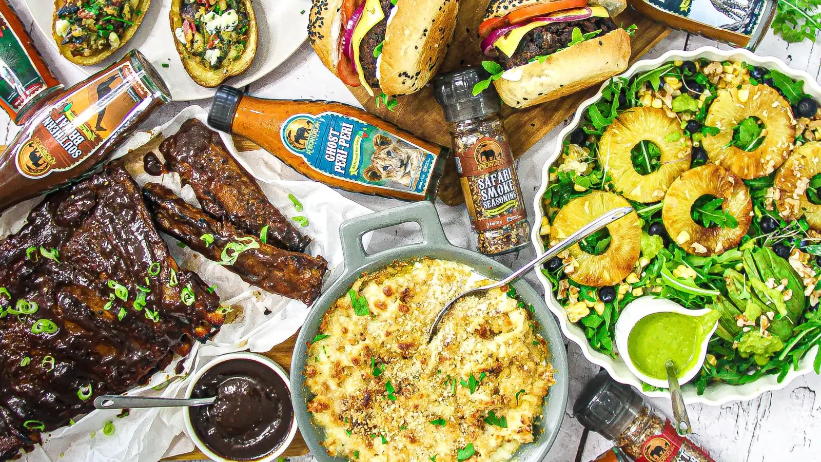 A beautifully arranged table featuring an assortment of foods, African Dream Foods hot sauce, seasonings and salt.