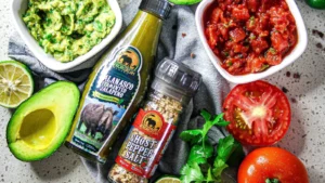 A close up of salsa and guacamole with African Dream Foods Jalanasco hot sauce and Ghost Pepper Salt.