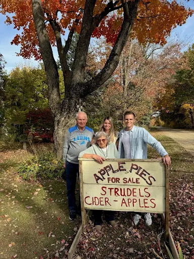 Bakr founder and her family stand behind a sign advertising apple pies and strudel for sale.