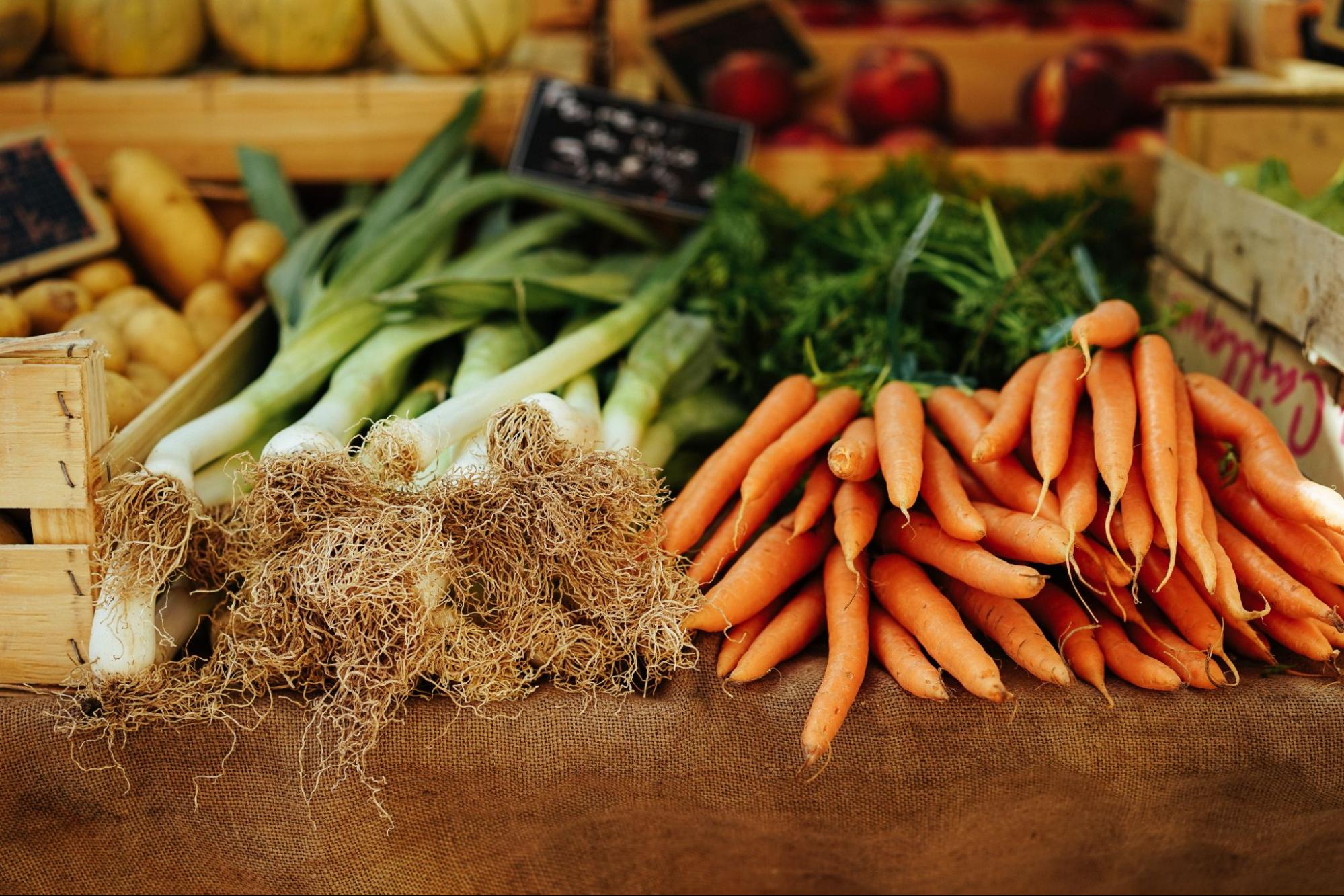 Closeup of a carrot bunch and spring onions on a farm table