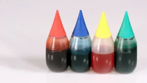 A set of plastic food coloring bottles with red, blue, yellow and green dyes against a white background.