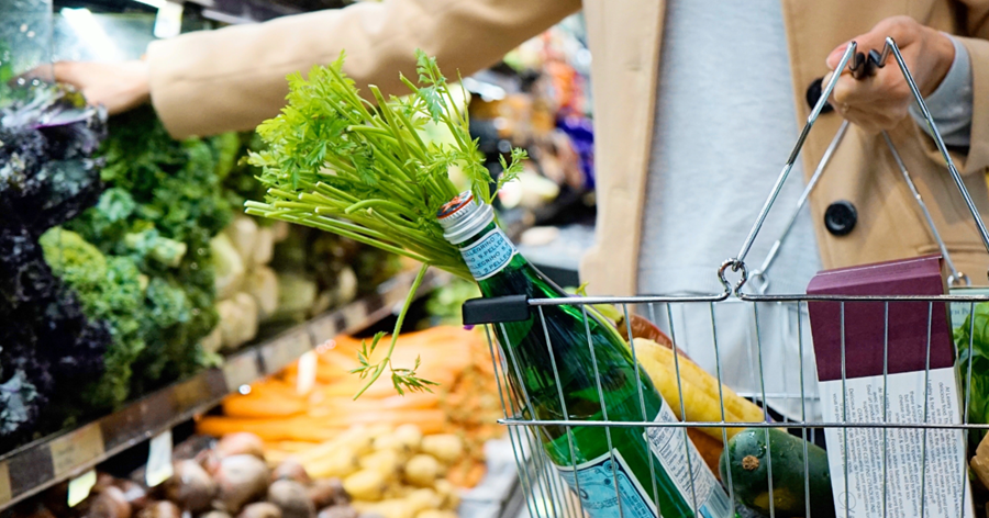 Herbs, water bottle, bananas in a grocery basked