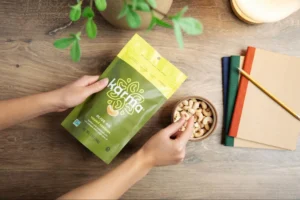 A person is snacking on cashews while looking at a package of Karma Nuts olive oil topped cashews at their desk.