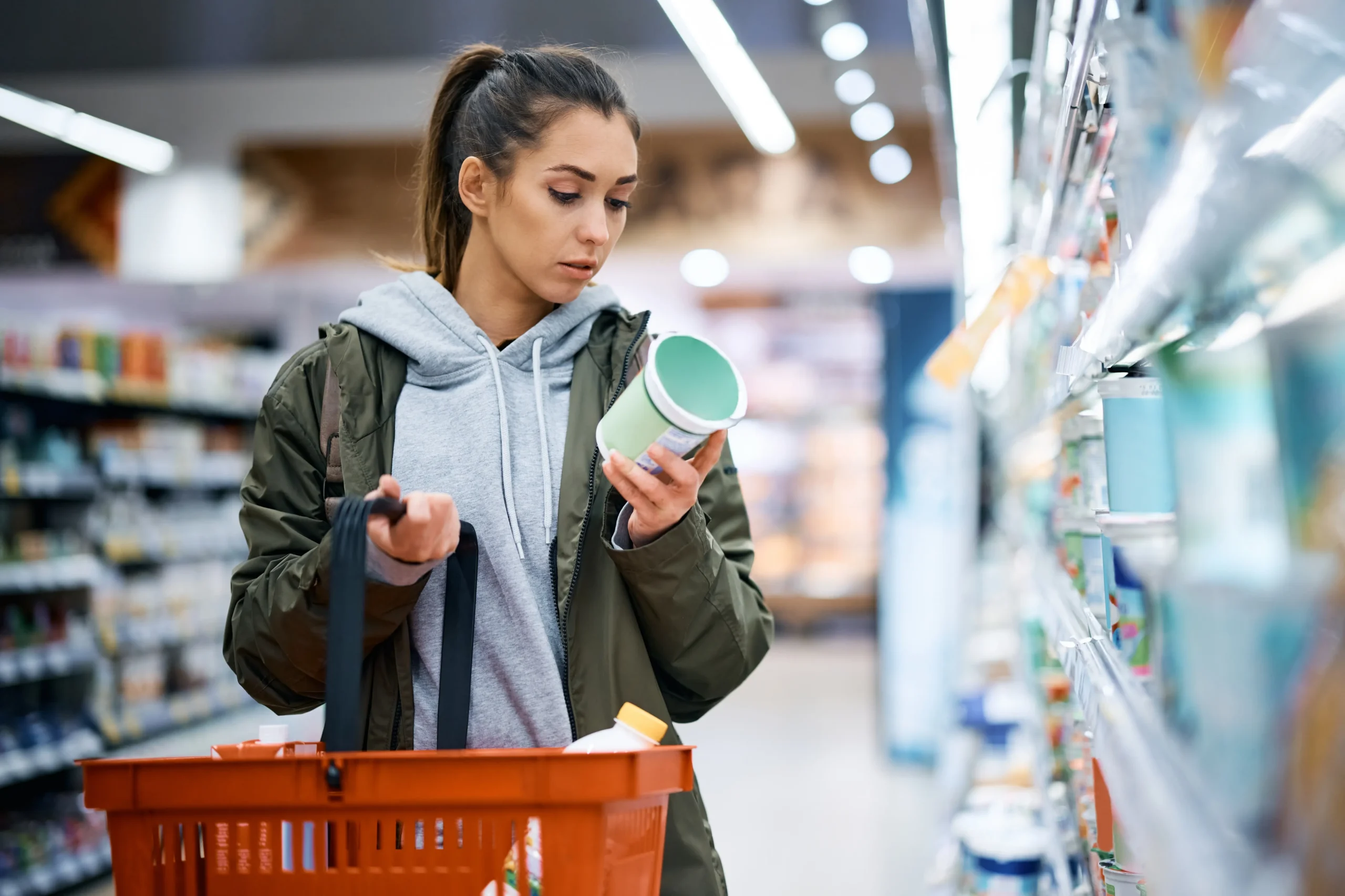 Young woman reads product label while buying dairy product in supermarket