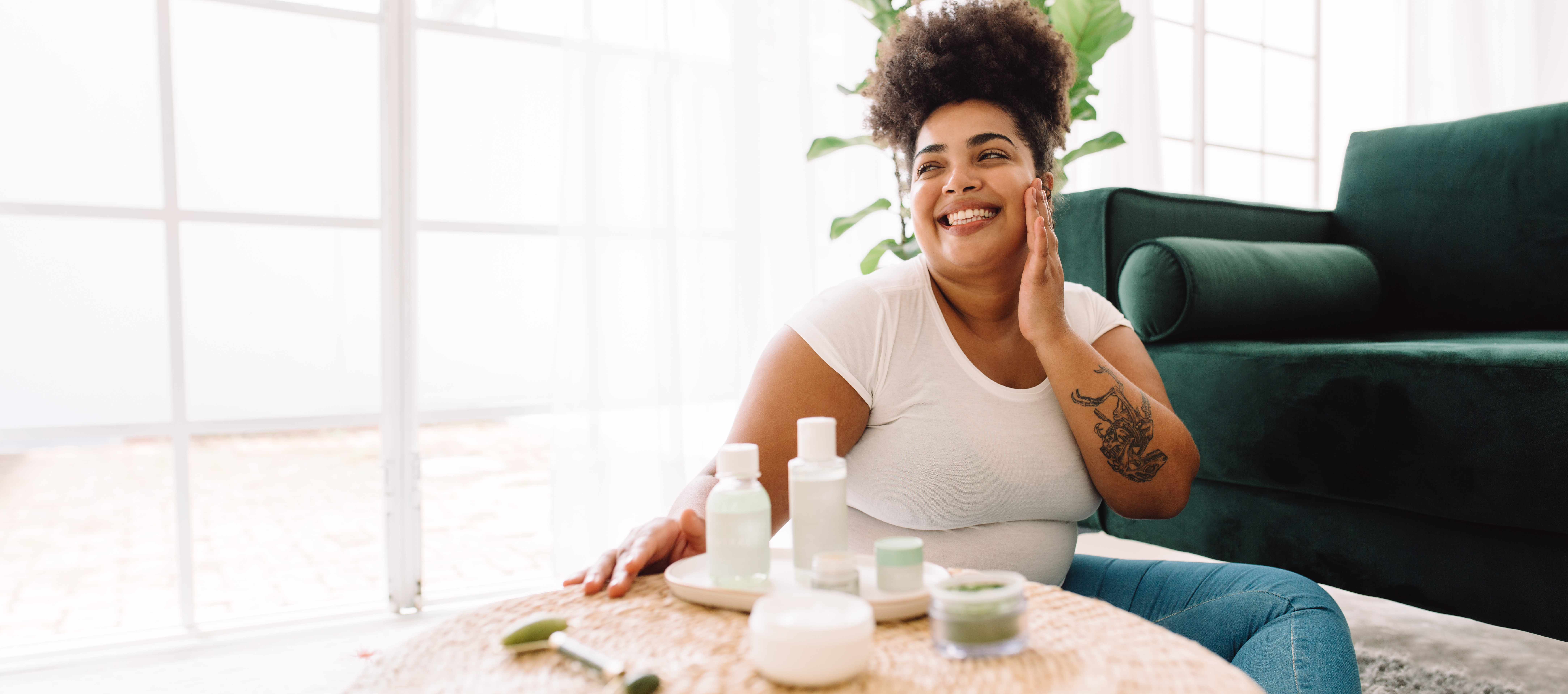 Attractive woman in living room looking happy after skin care at home. Happy female touching her face with hand at home.