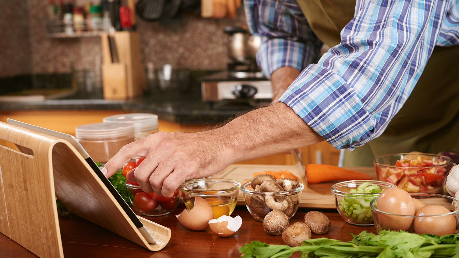 Left hand touching an ipad while prepping ingredients in the kitchen