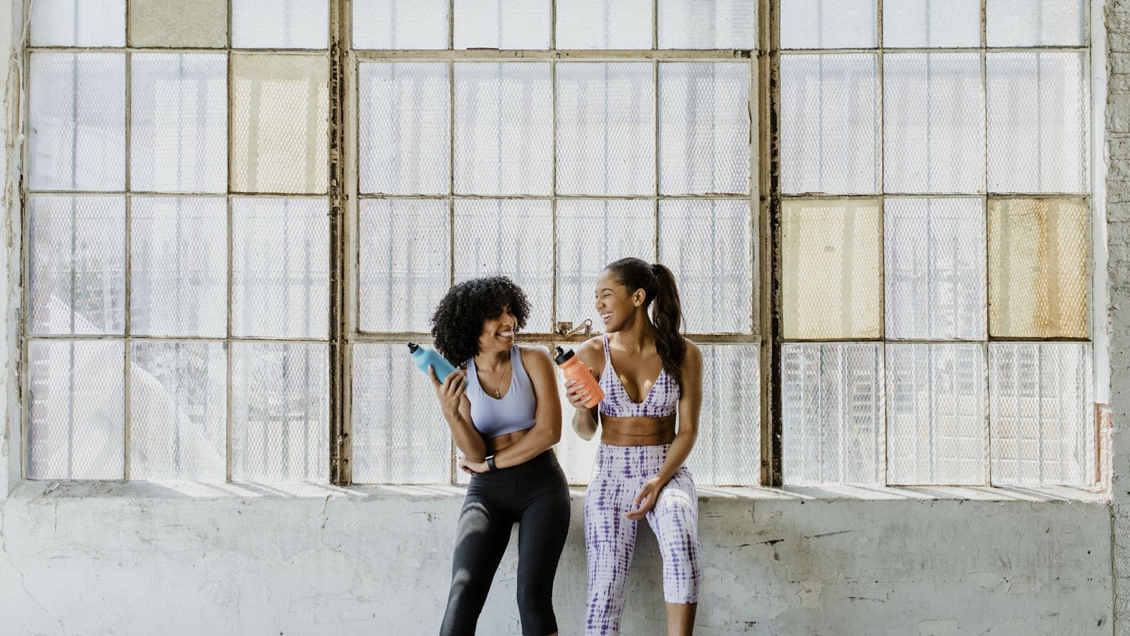 women in athletic attire holding beverage bottles